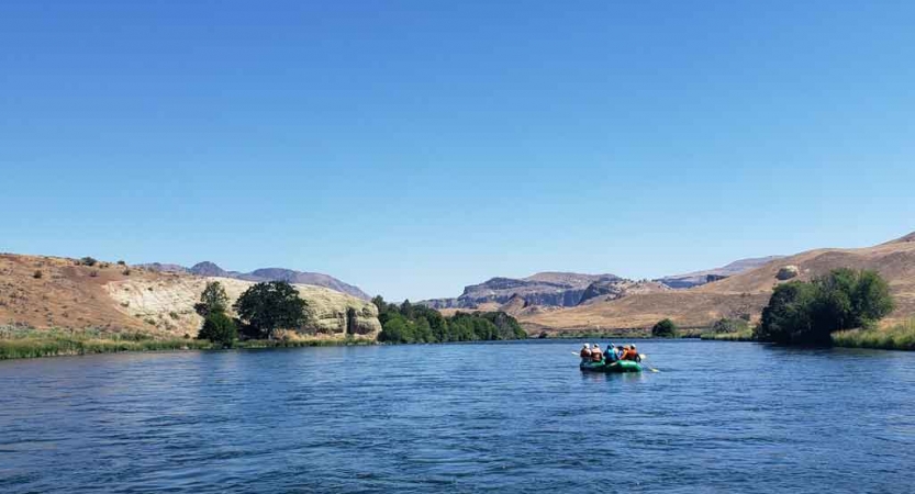 a raft is paddled by outward bound students on a calm river